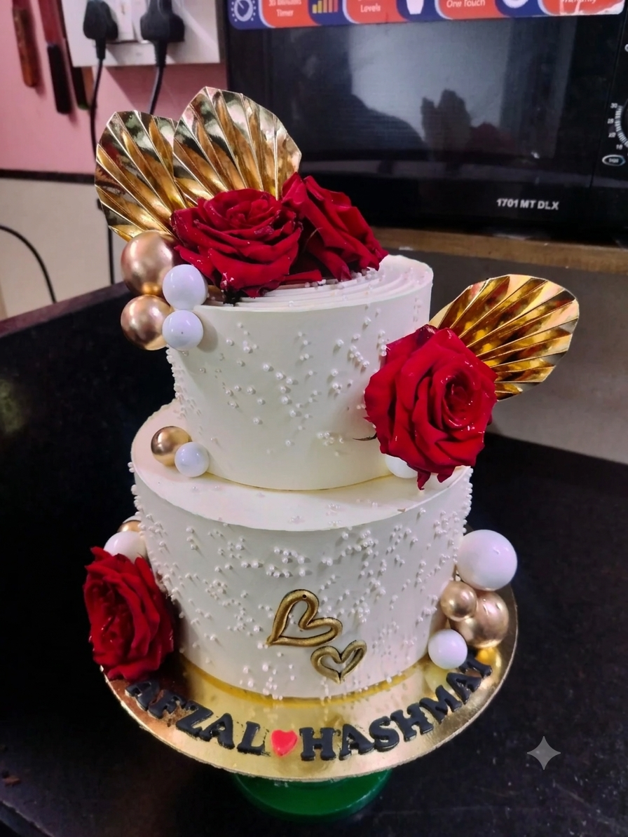 White tiered cake with red floral decorations and gold accents
