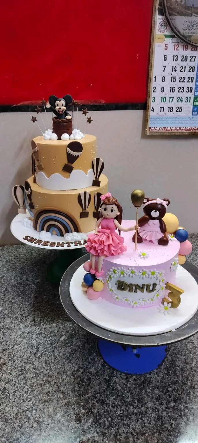 Two decorated celebration cakes on a bakery counter